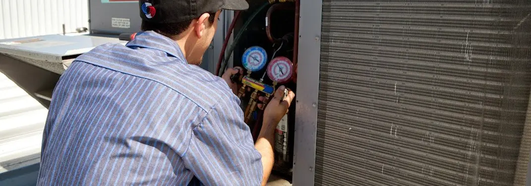 HVAC technician servicing a condenser unit in Belmont